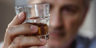 man holding up a glass of alcohol wondering how long does alcohol detox take?