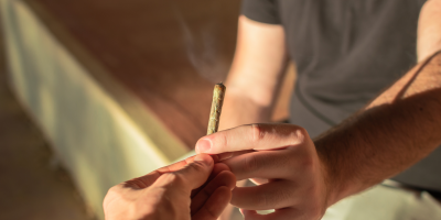 man handing another man a joint of marijuana