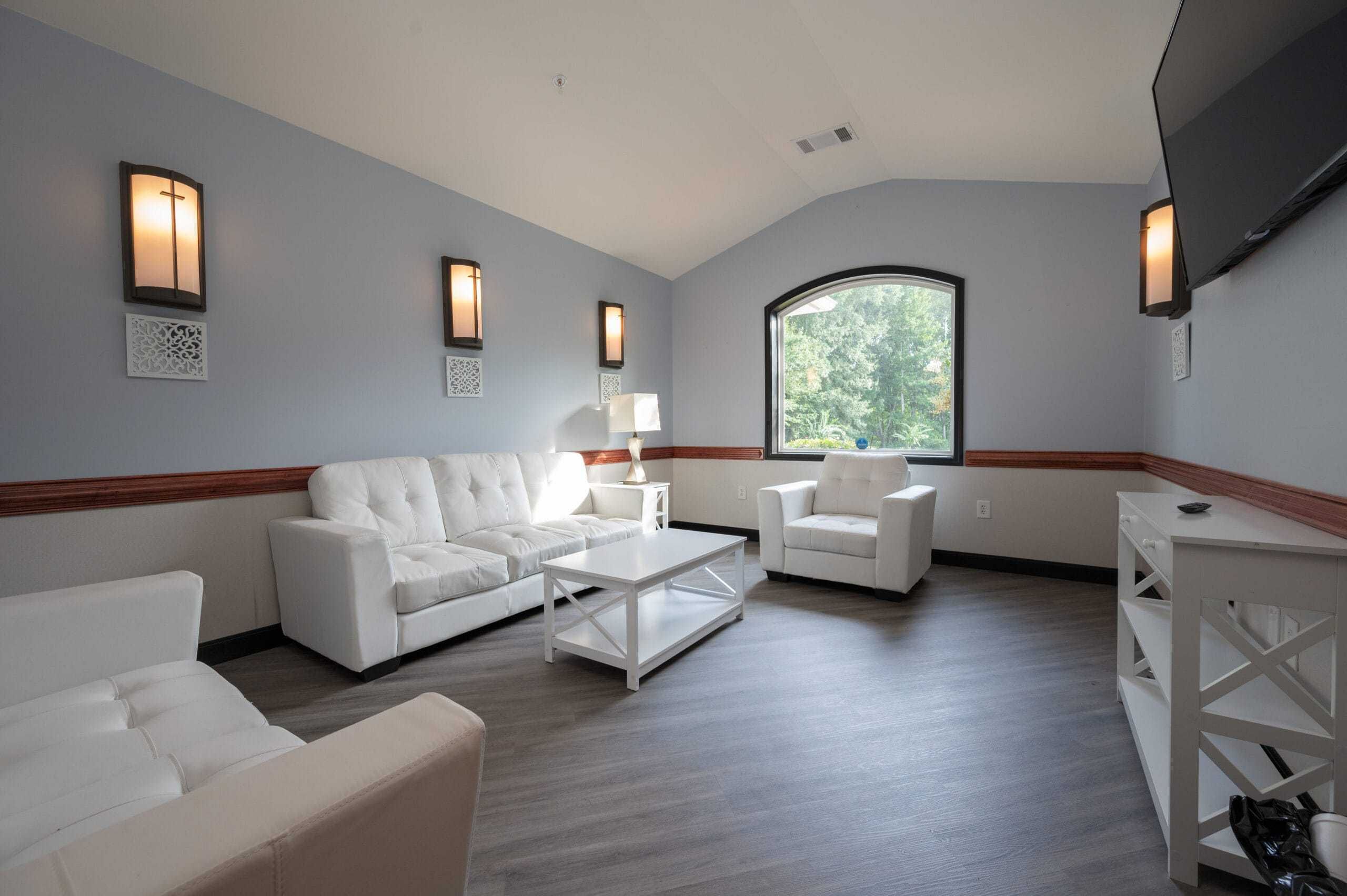 living room with white couches, chairs, and tables