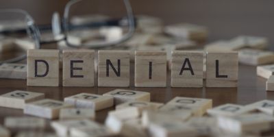 the word denial on individual scrabble tiles spelled out