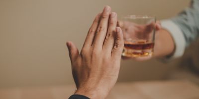 person puts up hand to refuse alcohol