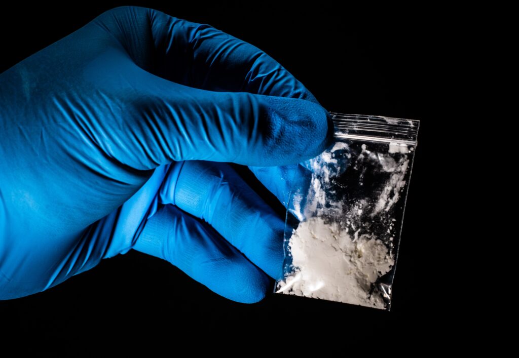 cocaine powder in a baggie handled by a gloved hand